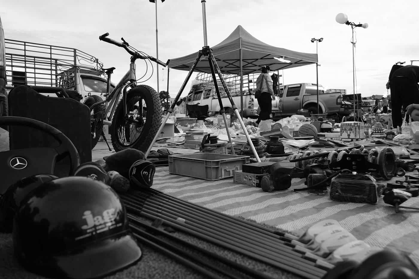 Shoppers browse goods spread under rows of canopy tents at an outdoor flea market